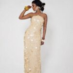 Woman wearing Solea, a butter yellow floor-length hand-stitched 3D paillette sequin halter dress by XELENE.